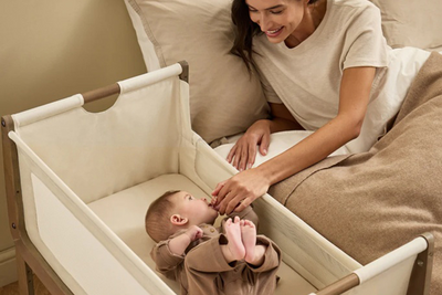 Mother interacting with a baby in a crib, both smiling and engaged.