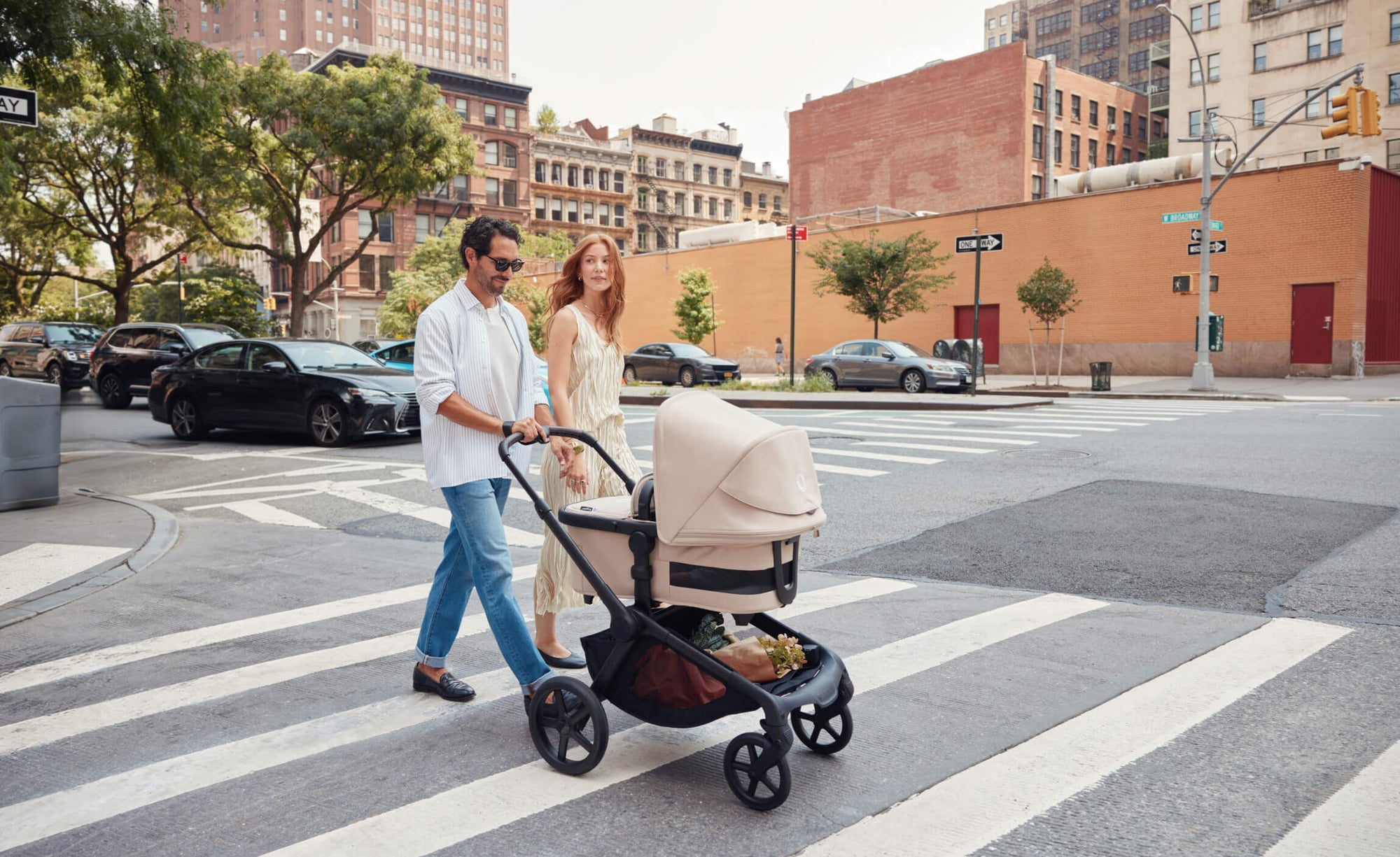 A couple walking with a stroller across a city street.