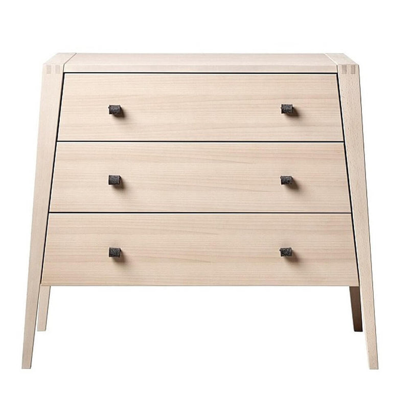 The Leander Linea Dresser by Leander features three soft-close drawers with double dark handles, angled legs, and a minimalist light wood design—ideal for nursery storage.