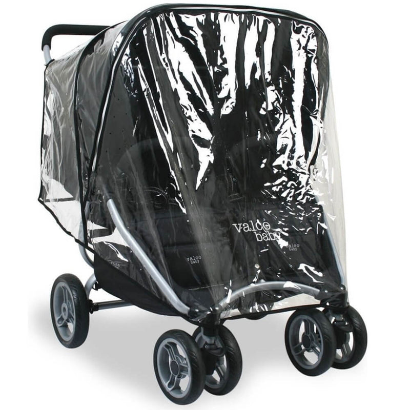A black-framed double stroller is protected from rain by the Valco Snap Duo Raincover, made from child-safe PVC, keeping seats dry. The Valco Baby brand name appears on the front.