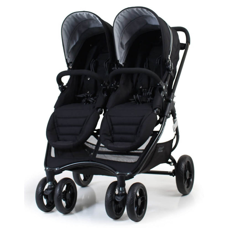 The Valco Baby Snap Ultra Duo Stroller by Valco Baby is a black, side-by-side stroller with two seats, padded footrests, front safety bars, four sets of wheels, and travel system compatibility for two children.