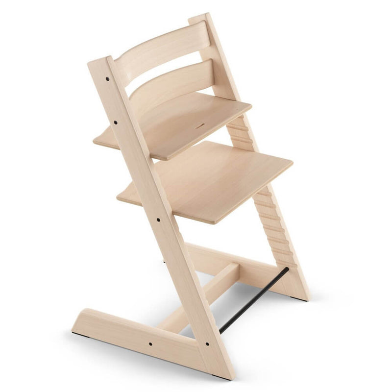 The Stokke Tripp Trapp Chair by Stokke is a wooden adjustable high chair with a natural finish, ergonomic seating, and repositionable seat and footrest to fit various heights.