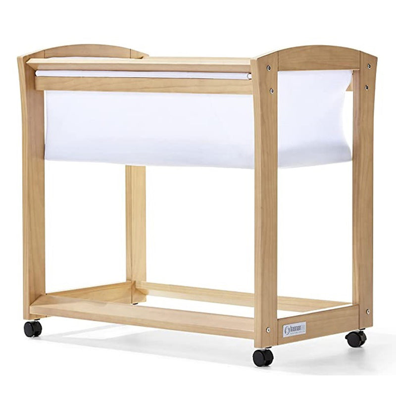 The Seena Amore Bassinet by Seena is a wooden baby bassinet made from sustainable timber, with a white fabric sling, open sides, and four black caster wheels for easy mobility.