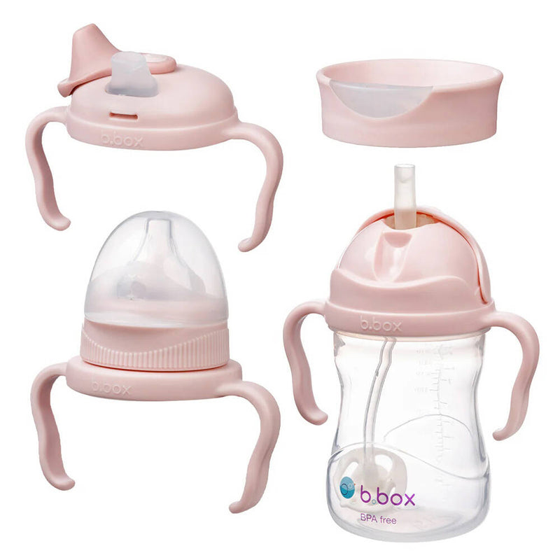The b.box Transition Value Pack for toddlers includes a pink sippy cup with side handles, measurement markings, and three interchangeable lids (straw, spout, and training cup) to support easy transitions.
