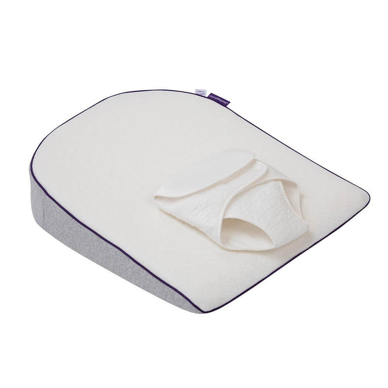 The Clevamama ClevaSleep Plus Elevated Support is a slanted memory foam pillow with a white textured cover, detachable support pad, light gray sides with purple trim, designed to help prevent Flat Head Syndrome and provide comfort.