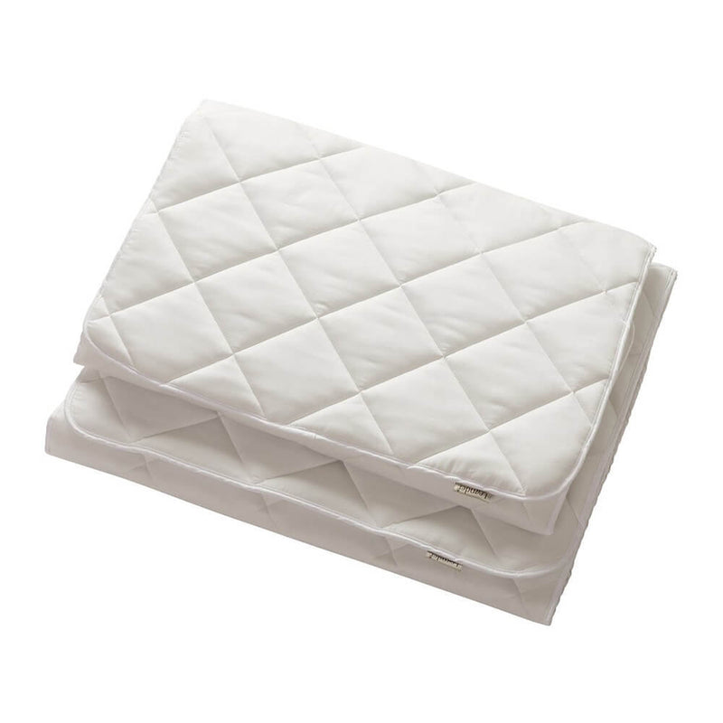 Two white, rectangular quilted pads with diamond stitching stacked on a white background—an ideal Leander Linea & Luna Cot Mattress Protector made from organic cotton for your baby's bed.