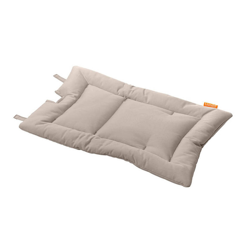 The Leander Chair Cushion by Leander is a rectangular, light beige padded cushion made from organic cotton, featuring stitched sections and small fabric loops on one side, shown lying flat on a white background.