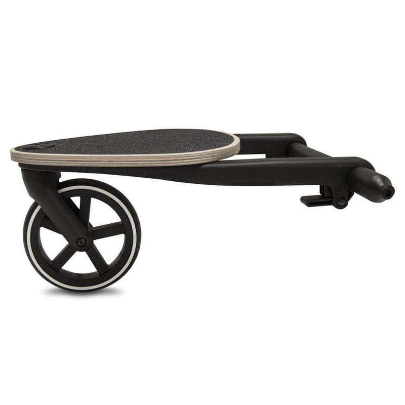 The Cybex Gazelle S Kid Board by Cybex is a black and wood stroller attachment with a large wheel and textured standing surface, allowing an older child to ride along with the Gazelle S Pram.