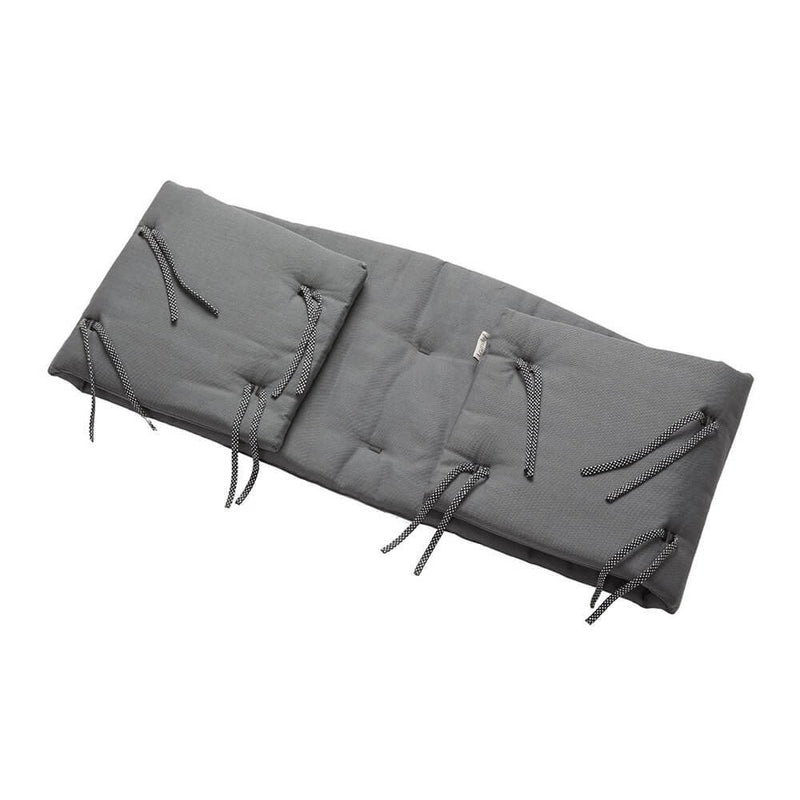 The Leander Classic Organic Cot Bumper by Leander is a soft, thick, gray, rectangular bumper made from organic cotton with black and white striped side ties for secure attachment to a cot or bench.