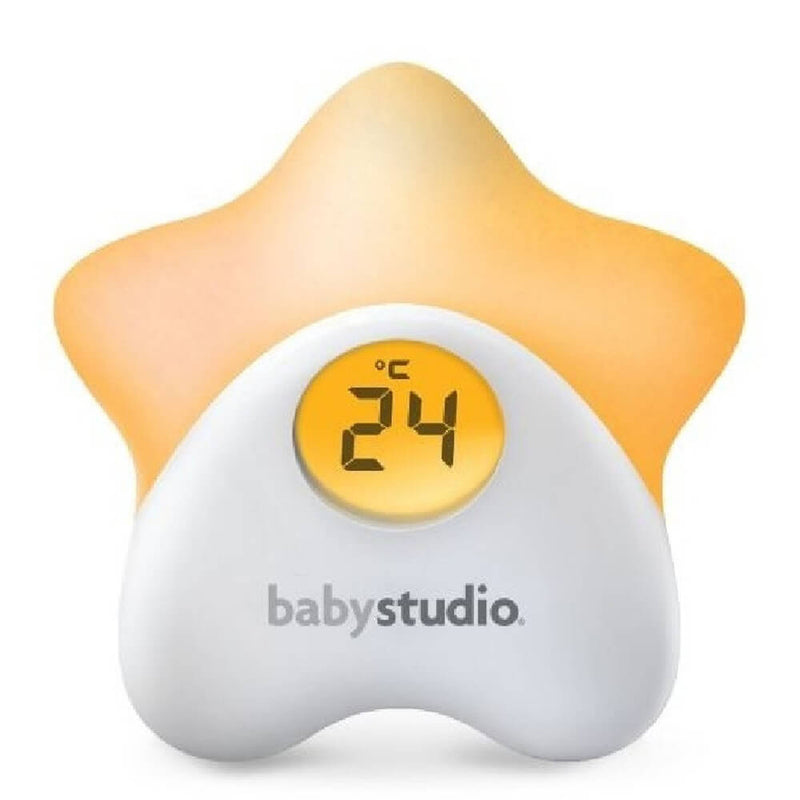 The Baby Studio Star Thermometer Night Light features a star-shaped design, yellow glow, and displays 24°C on a round screen. With "babystudio" in gray on the white base, it’s a charming, practical accessory for any nursery by Baby Studio.