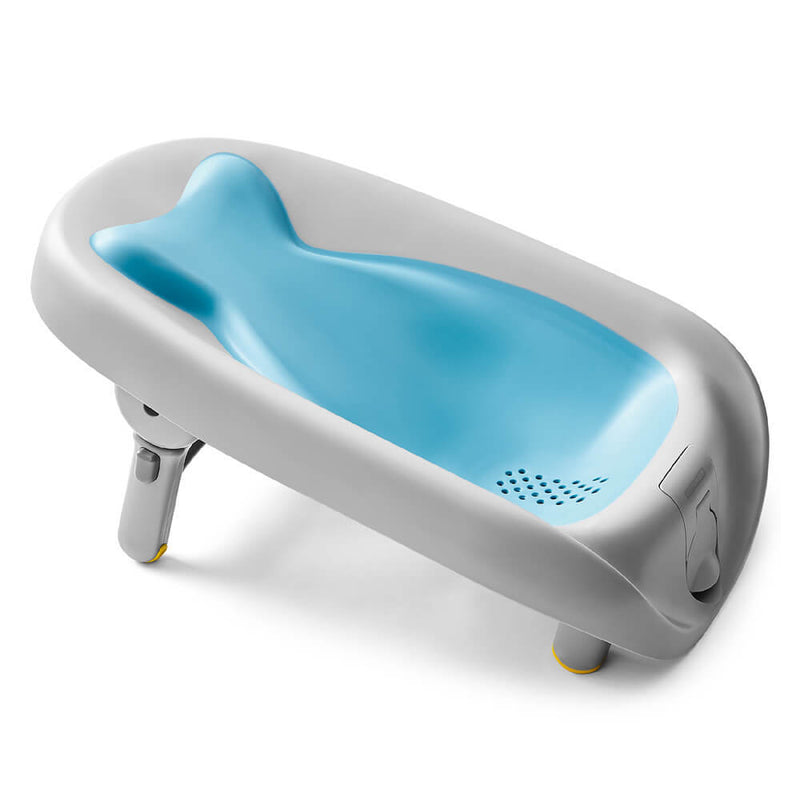 The Skip Hop Moby Recliner & Rinse Bather is a gray and blue plastic newborn tub with a contoured whale-shaped insert, foldable legs, drain holes at one end, and is designed by Skip Hop for convenient infant bathing.