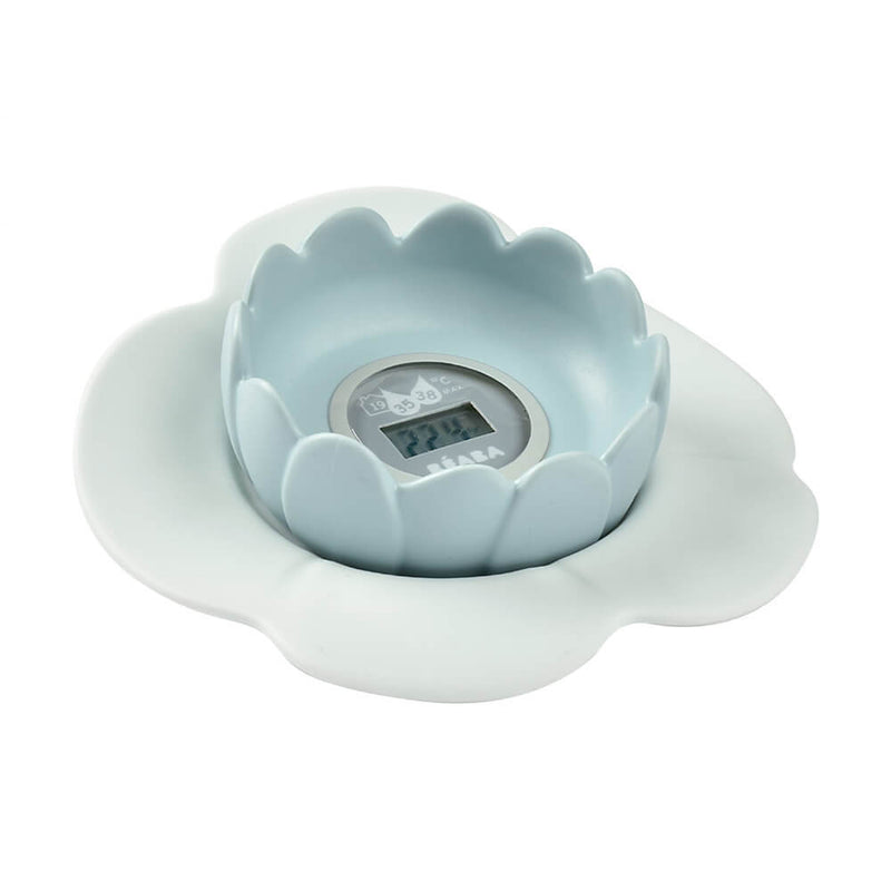 A light blue, flower-shaped Beaba Lotus Multifunctional Digital Thermometer by Beaba rests in a white, petal-shaped saucer. Its clear center display shows numbers, making it ideal as a baby bath thermometer.