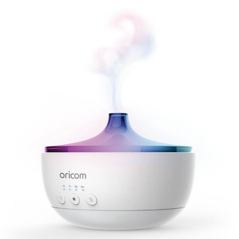 The Oricom 4-In-1 Aroma Diffuser, Humidifier, Night Light and Speaker emits a gentle stream of colorful vapor from its top, with control buttons on the front, against a plain white background.