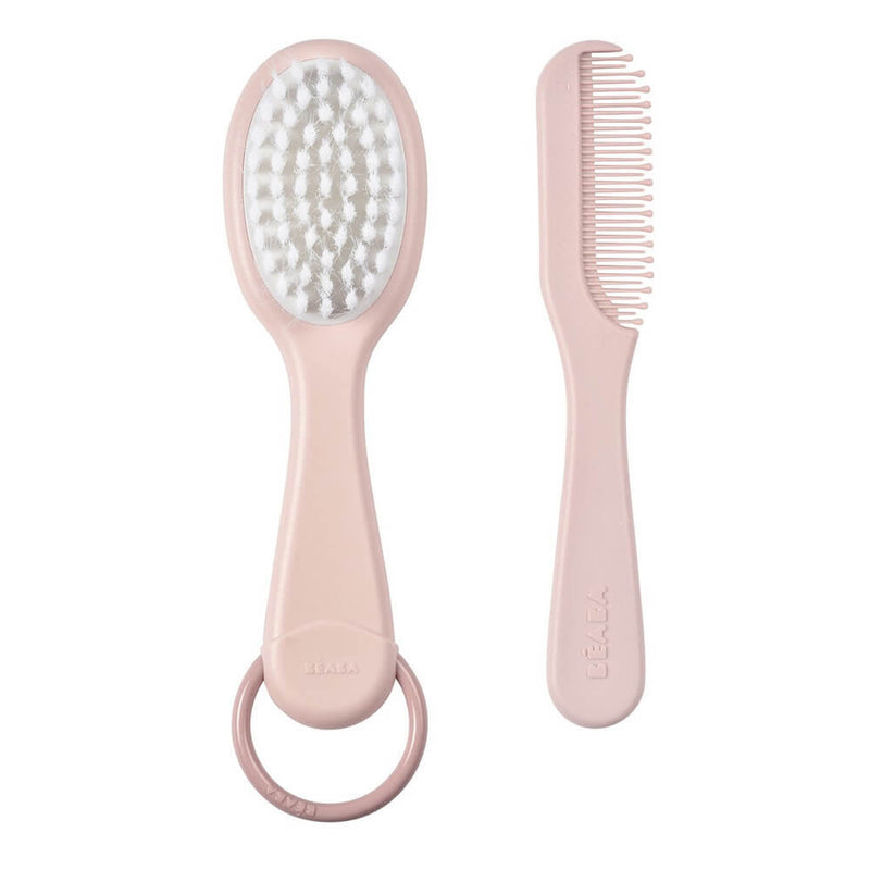 The Beaba Baby Brush & Comb set by Beaba features ergonomic handles, a pink brush with soft nylon bristles, and a circular ring for easy use—ideal for gentle baby grooming.