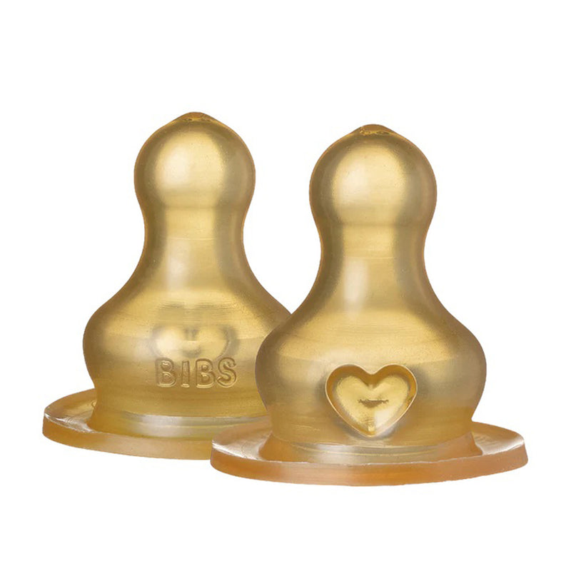Two BIBS Latex Teats from Bibs Dummies, designed for BIBS Glass Bottles, stand upright on a white background—one with a rounded top and the other with a heart-shaped opening on the base.