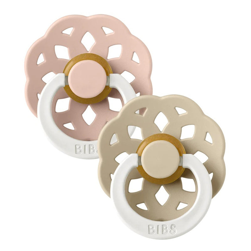 Two Bibs Dummies Boheme Night Glow Dummies with scalloped flower-shaped shields—one pale pink, one beige—feature glow-in-the-dark rings, circular centers, and "BIBS" embossed on each ring. Made with natural rubber latex.