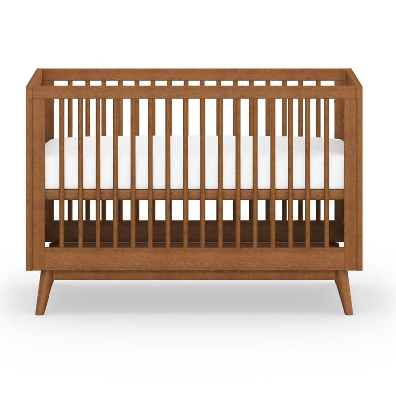 The BabyRest Kaya Cot by BabyRest is a wooden crib with vertical slats, a sturdy rectangular frame, and a white mattress, featuring mid-century modern style against a plain white background.