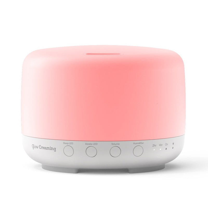 The Glow Dreaming Sleep Easy by Glow Dreaming is a pink and white smart sleep device and diffuser with labeled buttons for sleep/awake LED, volume, timer, power, mode settings, plus pink noise for enhanced relaxation.