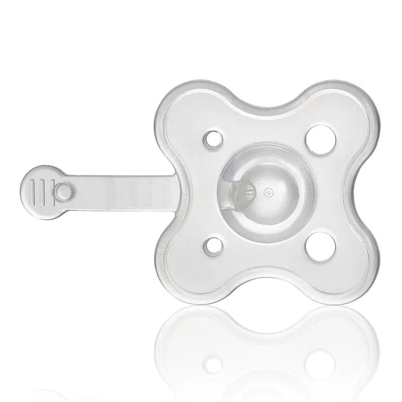 The Frida Baby Medi Frida, a transparent silicone pacifier with a flat, flower-shaped shield and four round ventilation holes, is designed for easy medicine dosing and shown against a white background.