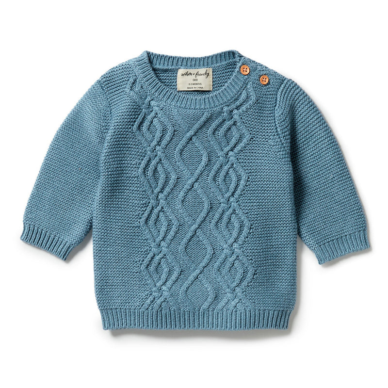 The Wilson & Frenchy Knitted Cable Jumper Bluestone is a soft cotton-bamboo-wool blend knit with a wavy cable front, two wooden shoulder buttons, and a charming light blue hue—an ideal winter essential for little ones.