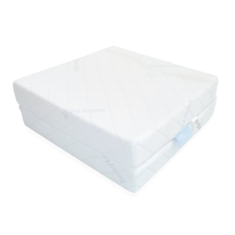 The BabyRest Comficore Dixie Folding Cot Mattress by BabyRest is a white, rectangular mattress with a quilted diamond-pattern cover, shown partially folded. A small fabric tag is attached to one corner.