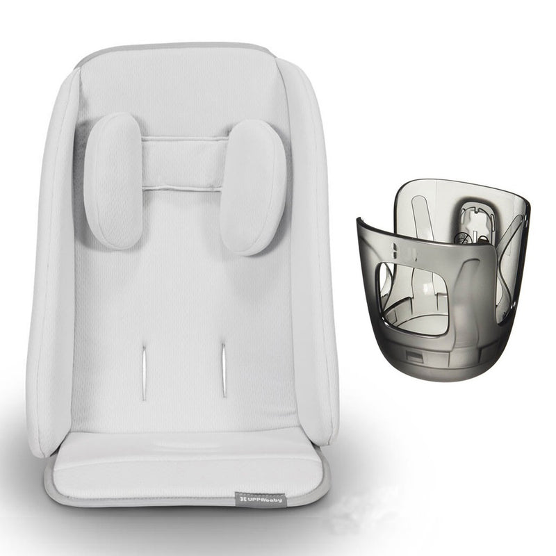 The UPPAbaby Cruz Accessory Bundle from UPPAbaby features a light gray padded car seat liner with head support, displayed beside a transparent car seat shell that reveals the internal structure.