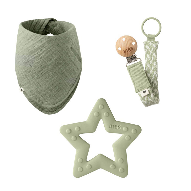 The BIBS My First 6 Months set by Bibs Dummies includes a sage green muslin bandana bib, star silicone teether, and pacifier clip with a wooden button—an ideal baby shower gift.