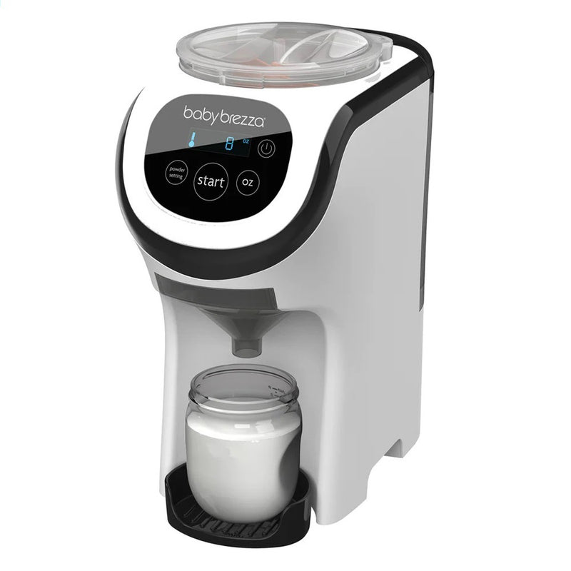 The Baby Brezza Formula Pro Mini, a compact white and black formula dispenser, is shown preparing warm formula into a baby bottle on its tray. It features a digital control panel with settings buttons and a transparent lid.
