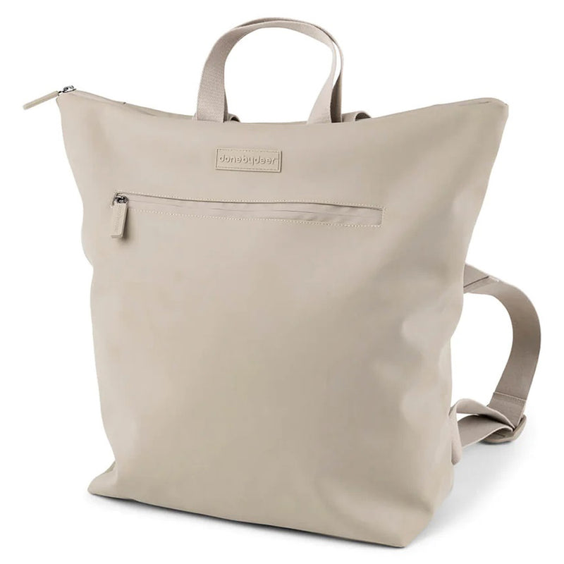 The Done By Deer Changing Backpack Sand by Done By Deer is a beige, minimalist changing bag with a top handle, adjustable shoulder straps, front zippered pocket, smooth matte finish, and a subtle logo above the front pocket.