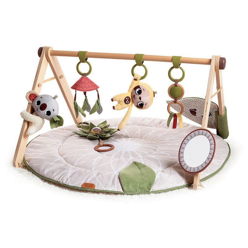 The Tiny Love Boho Chic Luxe Gymini by Tiny Love features a soft, round activity mat with hanging plush toys such as a koala and giraffe, a small mirror, and colorful elements to stimulate and entertain infants.