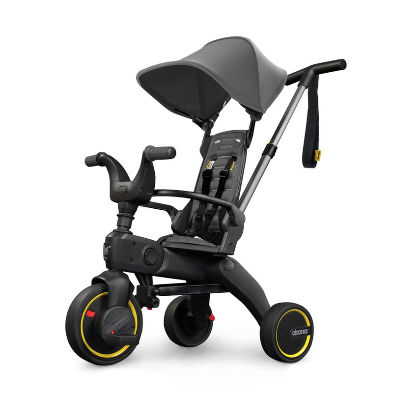 The Doona Liki Trike S1 Grey Hound by Doona is a stylish grey folding trike with a sun canopy, handlebars, footrests, safety harness, and an adult push handle—ideal for travel and compact storage.