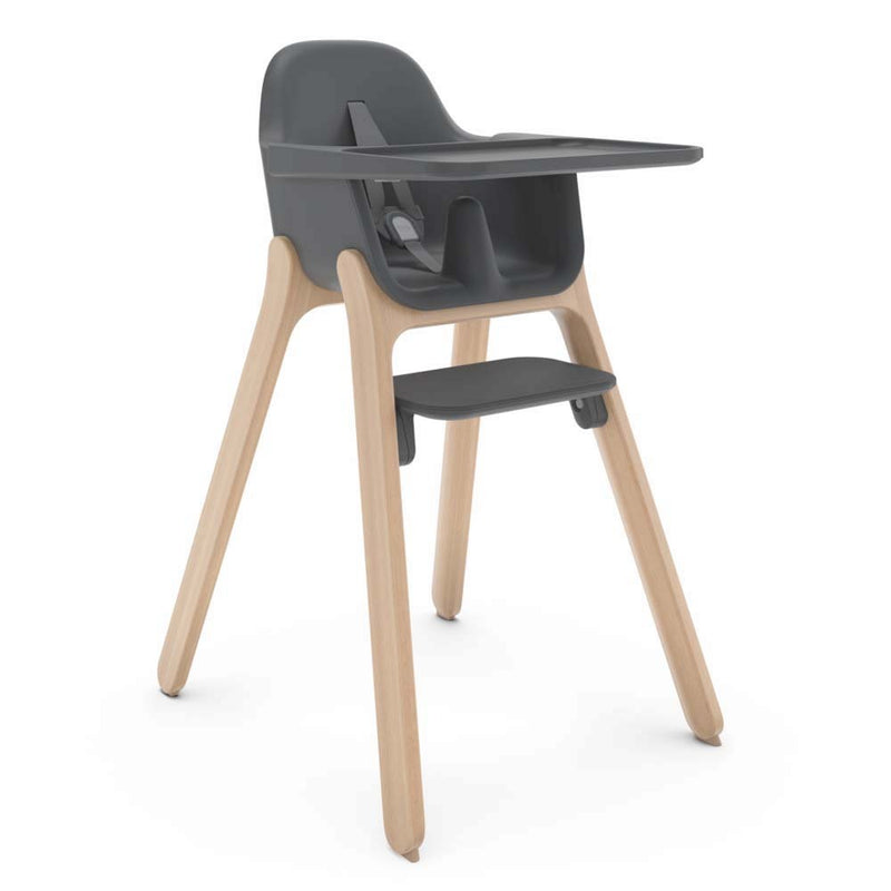 The UPPAbaby Ciro High Chair by UPPAbaby features a dark gray plastic seat, tray, and footrest with four light wooden legs, a safety harness, and a sleek, minimalist design that's easy to clean.