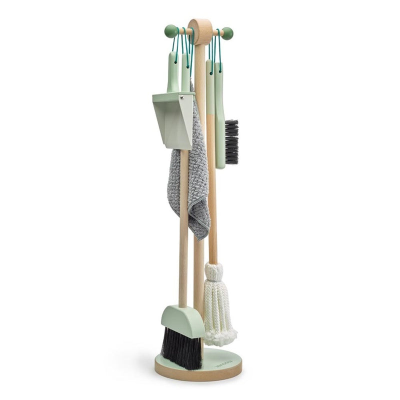 The Moover Toys Essentials Cleaning Set Green by Moover features a broom, mop, dustpan, brush, and cloth with light green handles on a circular wooden stand—perfect non-toxic pretend play tools for kids.