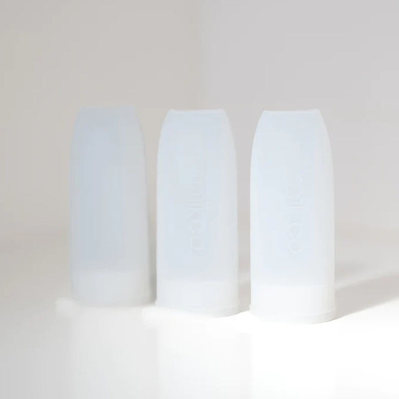 Three clear Milkco Breast Milk Ecopods by Milkco stand upright on a white surface, perfect for eco-friendly baby products or breast milk storage, with soft light highlighting their sleek, food-grade silicone design.