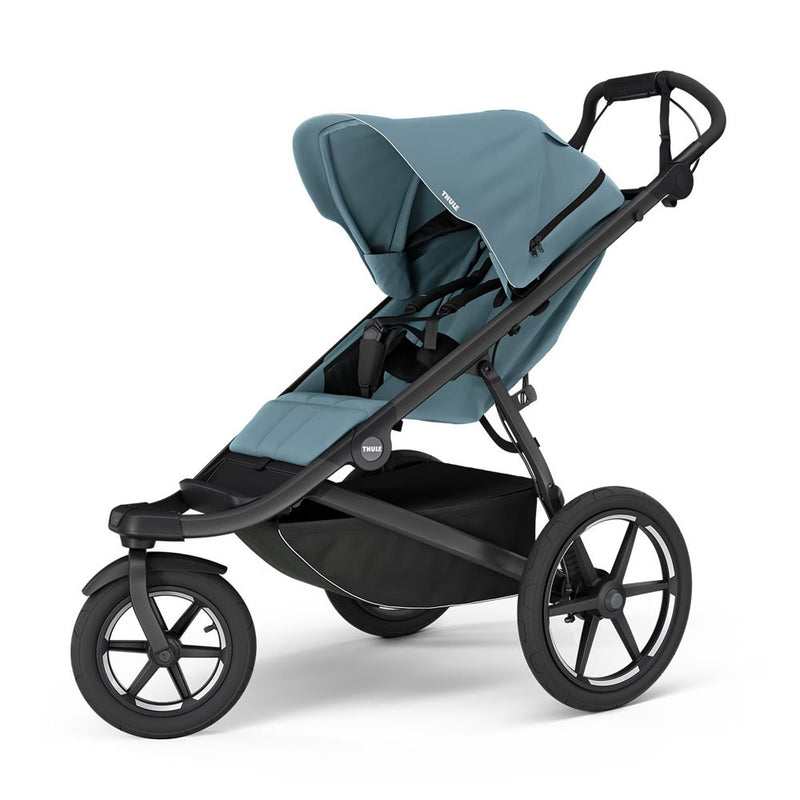 The Thule Urban Glide 3 Mid Blue Stroller by Thule is a modern all-terrain stroller featuring three large air-filled tires, a mid blue canopy, black frame, spacious seat, safety harness, roomy storage basket, and adjustable handlebar.
