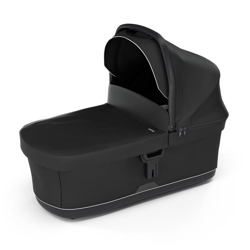 The Thule Urban Glide 3 Bassinet Black by Thule is shown on a white background. It features a detachable hood, zipper, curved canopy, rectangular base, and ventilated mattress for comfort in a modern, sleek design.