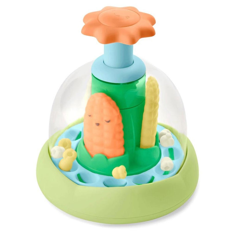 The Skip Hop Farmstand Push & Spin Baby Toy features a green base, blue platform, clear dome, orange flower top, and popcorn figures—ideal for engaging baby’s senses and encouraging fine motor development.