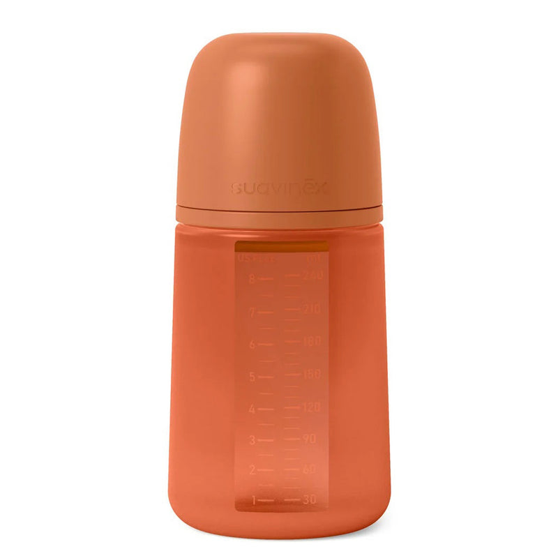 The Suavinex All Silicone Bottle 240ml is a matte orange, microplastics-free baby bottle with a matching cap, measurement markings on the side, and "suavinex" embossed near the top.