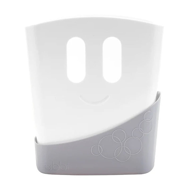 The Ubbi Bath Toy Drying Bin Grey by Ubbi features two vertical oval holes and a curved slit resembling a smiling face, set in a gray base with a circular pattern and the "Ubbi" logo embossed on it.