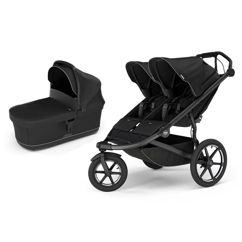 The Thule Urban Glide 3 Double Stroller + Bassinet Black by Thule features two side-by-side seats and a matching black bassinet, both with sun canopies, set against a white background for comfortable, stylish all-terrain strolling.