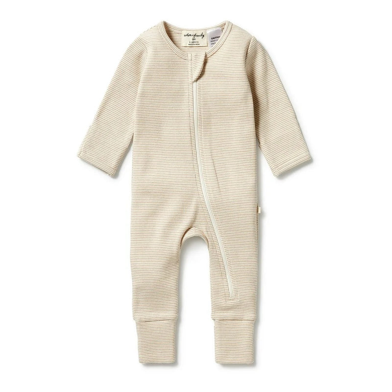 The Wilson & Frenchy Organic Stripe Rib Zipsuit With Feet Oatmeal is a beige, long-sleeve newborn sleepsuit in soft organic cotton with subtle stripes and a diagonal front zipper, shown laid flat on a white background.