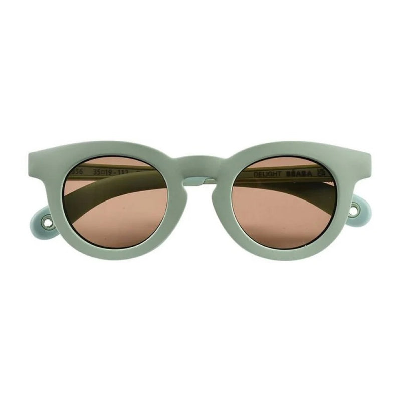 Front view of Beaba Baby Sunglasses 9-24 Months Delight Sage Green by Beaba, featuring light green frames, brown shatter-resistant lenses, and keyhole-shaped details near the hinges for enhanced UV protection.