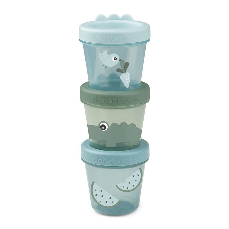 The Done By Deer Baby Food Container 3-Pack Croco Green includes three pastel, leakproof, stackable snack containers with lids, playful crocodile and fruit illustrations, and "done by deer" branding on each.