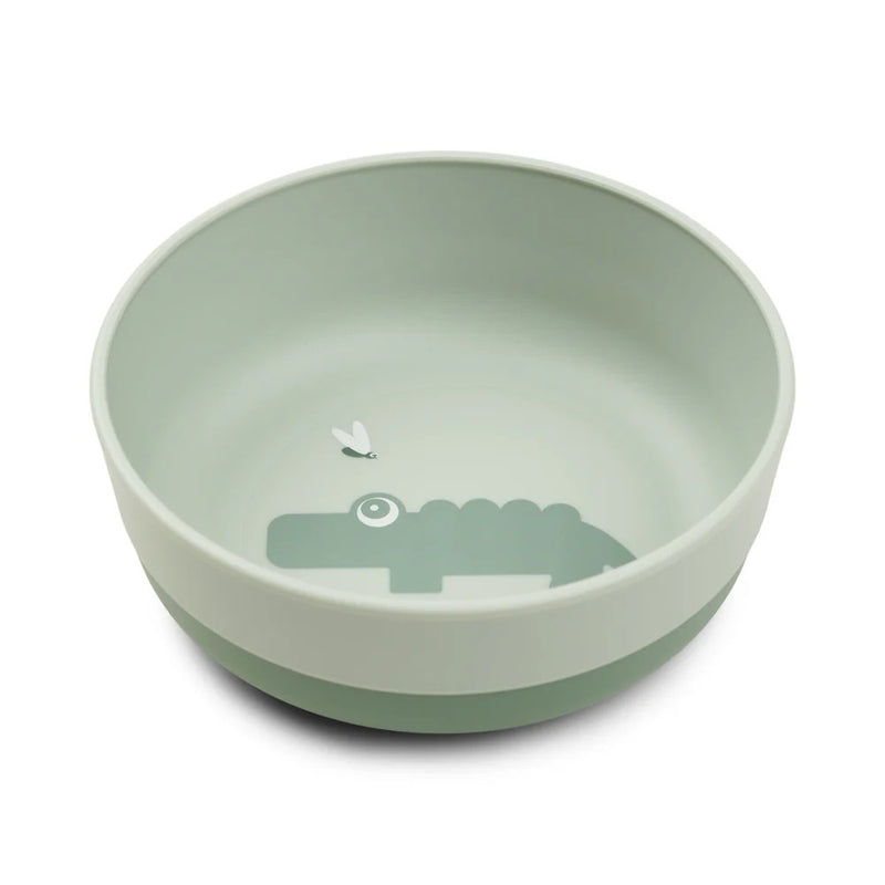 The Done By Deer Foodie Bowl Croco Green is a light green kids bowl from Done By Deer, featuring a simple crocodile illustration with an insect inside the base and an anti-slip base for stability.