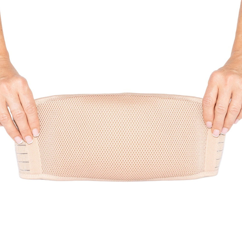 Two hands hold a Partum Panties Pregnancy Support Band by Partum Panties, stretching the beige band horizontally against a white background.