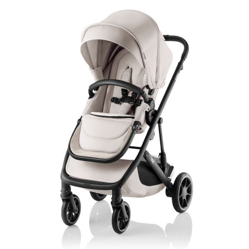 The Britax Safe-n-Sound Mini Stroller is a lightweight beige single stroller with a canopy, reversible padded seat, safety harness, black frame, four wheels, footrest, and removable front bar—newborn ready and easy to maneuver.