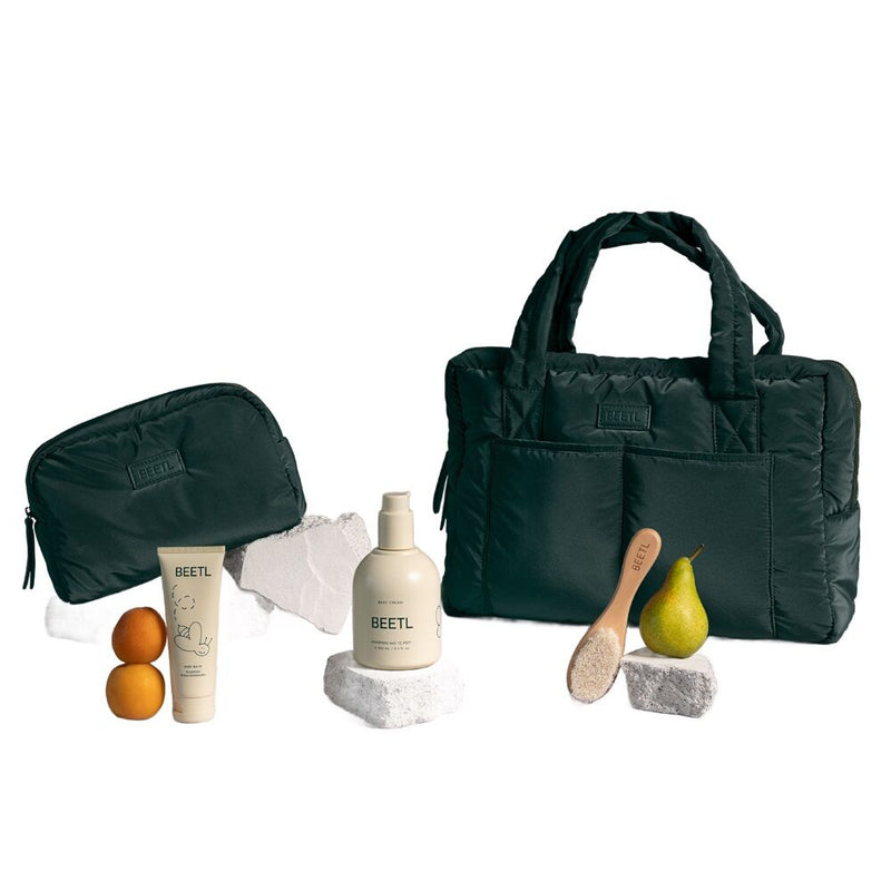 The BEETL Baby Ultimate Giftset features green bags, a baby bag, toiletry pouch, BEETL Baby Cream, skincare items, lotion bottle, wooden brush, pear, apricots & white towels—perfect for a thoughtful baby shower gift.