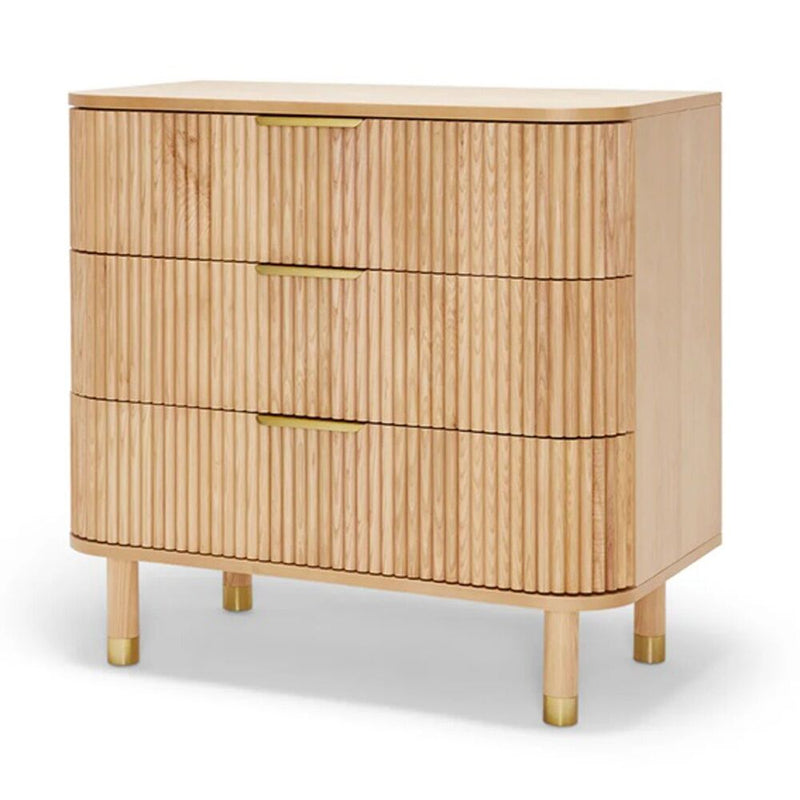 The BabyRest Juno Chest 3 Drawer by BabyRest features solid timber, vertical grooves, gold handles, rounded corners, and short legs with gold caps—making it a stylish and durable choice for any nursery.