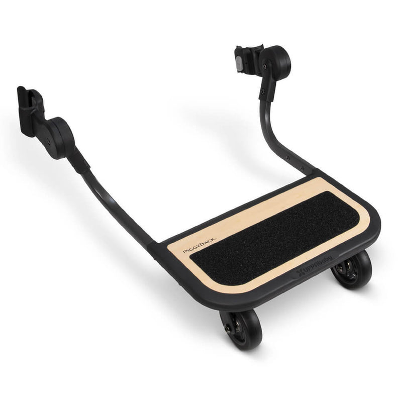 The UPPAbaby Piggyback Board CRUZ V2/V3 is a black and wood ride-along board with two wheels. It attaches to your stroller, letting a child stand and ride safely on its textured grip platform—perfect for UPPAbaby CRUZ families on the go.