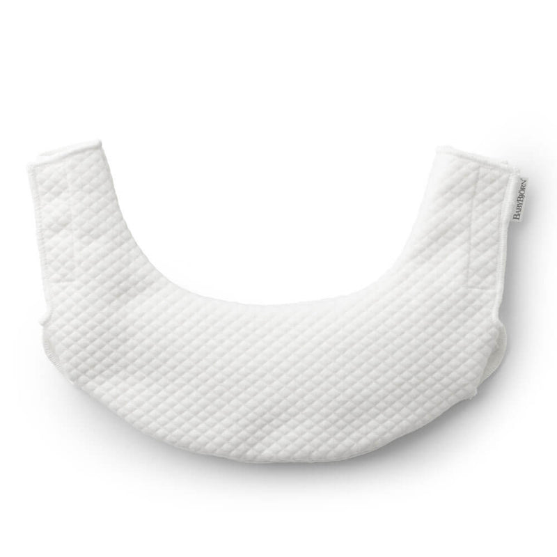 The BabyBjorn Carrier One Bib is a white, quilted, crescent-shaped teething bib with a soft textured surface. Shown on a plain white background, it features a small fabric tag and is perfect for your BabyBjorn Carrier One.